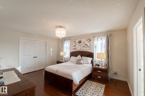Wood-finish flooring, white double doors with arch detailing, a crystal chandelier, and light-toned walls - 914 Crystallina Nera Way Nw, Edmonton, AB 