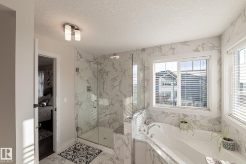 Glass-enclosed shower, built-in soaking tub, large window, tile flooring, and wall tile - 914 Crystallina Nera Way Nw, Edmonton, AB 