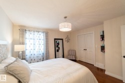 Hardwood-finish flooring, white double-door closet, drum pendant light fixture, and a window with curtain rod - 