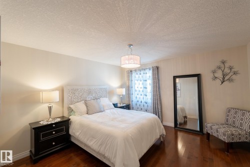 Wood-finish flooring, patterned accent wall, and a drum pendant light fixture - 914 Crystallina Nera Way Nw, Edmonton, AB 