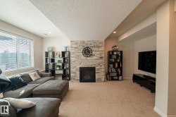 Fireplace with stone surround, recessed lighting, large window with blinds, and carpeted flooring - 