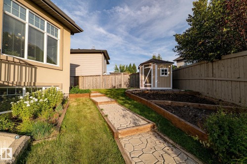 Multi-level backyard featuring a paver stone pathway, raised garden beds, and a hexagonal shed - 914 Crystallina Nera Way Nw, Edmonton, AB 