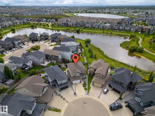Cul-de-sac residence with a two-story elevation, multiple rooflines, and a paved driveway, situated in a neighborhood featuring a prominent body of water and surrounding green spaces - 914 Crystallina Nera Way Nw, Edmonton, AB 