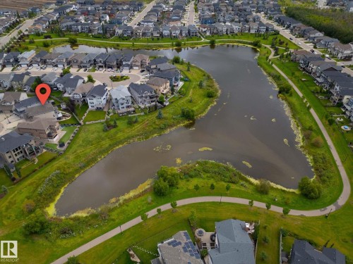 Waterfront property featuring a private patio, manicured lawn, and paved walking paths - 914 Crystallina Nera Way Nw, Edmonton, AB 