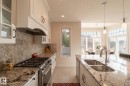 White cabinetry, stainless steel appliances, patterned backsplash, granite countertops, and a double basin sink - 914 Crystallina Nera Way Nw, Edmonton, AB 