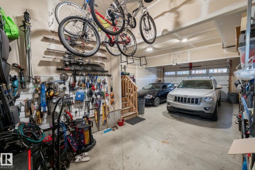 Two-car garage with concrete flooring, built-in storage shelving, and an interior wooden staircase - 914 Crystallina Nera Way Nw, Edmonton, AB 