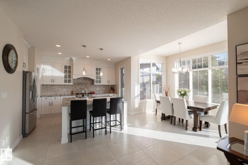 Kitchen featuring white cabinetry, stainless steel appliances, granite countertops, and a tile backsplash - 914 Crystallina Nera Way Nw, Edmonton, AB 