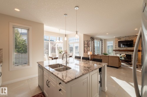Kitchen island with dual basin sink and stone countertop, recessed lighting, and pendant lighting fixtures - 914 Crystallina Nera Way Nw, Edmonton, AB 