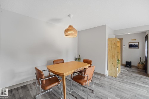 Dining area featuring wood-finish flooring, a woven pendant light fixture, and light-toned wall finishes - 17621 10 Avenue Sw, Edmonton, AB - Indoor Photo Showing Dining Room