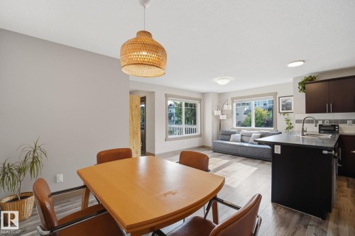 Open-concept living area featuring wood-finish flooring,  with dark cabinetry, and multiple windows. - 17621 10 Avenue Sw, Edmonton, AB - Indoor Photo Showing Other Room