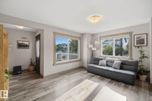 Spacious living area featuring neutral wall tones, and two large windows - 17621 10 Avenue Sw, Edmonton, AB - Indoor Photo Showing Living Room