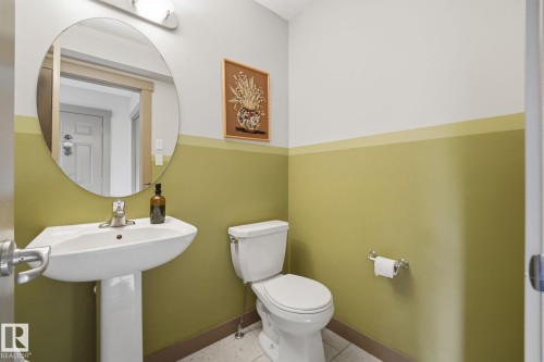 Pedestal sink with chrome faucet, oval mirror, and overhead vanity lighting - 17621 10 Avenue Sw, Edmonton, AB - Indoor Photo Showing Bathroom