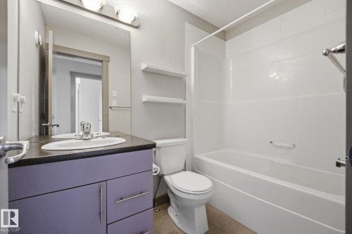 Bathroom featuring a white tub and shower surround, a toilet, and a vanity with a lavender base - 17621 10 Avenue Sw, Edmonton, AB - Indoor Photo Showing Bathroom