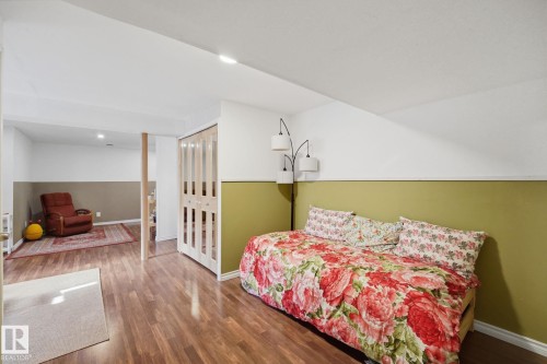 Lower level space featuring wood-finish flooring, white and olive green wall finishes, and bi-fold closet doors - 17621 10 Avenue Sw, Edmonton, AB - Indoor Photo Showing Bedroom
