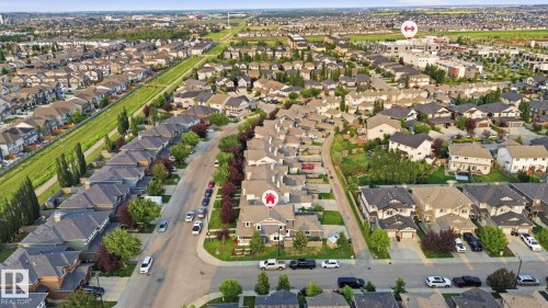 Aerial perspective showcasing a residential neighborhood with numerous homes, tree-lined streets, and open green spaces - 17621 10 Avenue Sw, Edmonton, AB - Outdoor With View