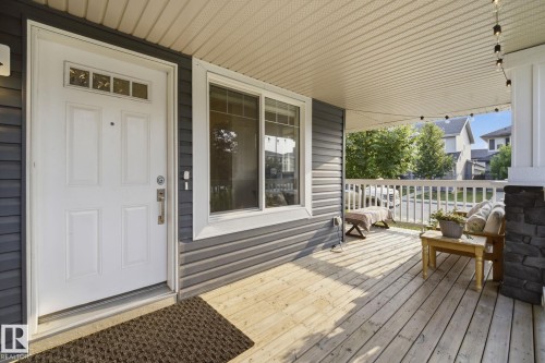 Inviting covered front porch with natural wood decking and white railing - 17621 10 Avenue Sw, Edmonton, AB - Outdoor With Deck Patio Veranda With Exterior