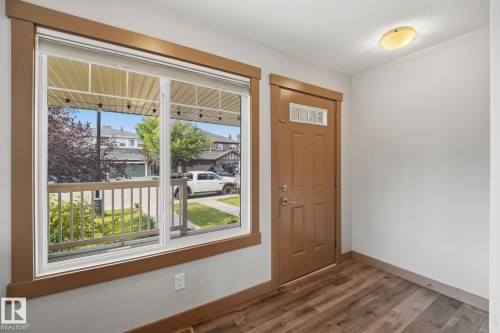 Entryway featuring a panel door with an integrated window, wood-finish flooring, and a large window overlooking the front porch - 17621 10 Avenue Sw, Edmonton, AB - Indoor Photo Showing Other Room