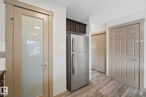 Frosted glass paneled pantry door with brushed nickel hardware, stainless steel refrigerator - 17621 10 Avenue Sw, Edmonton, AB - Indoor