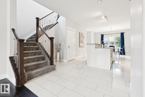 Staircase featuring dark wood newel posts and railings with decorative metal balusters - 9919 79 Street Nw, Edmonton, AB 