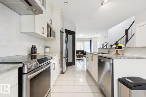 White cabinetry with stainless steel appliances, light-toned tile flooring, and granite countertops - 9919 79 Street Nw, Edmonton, AB 