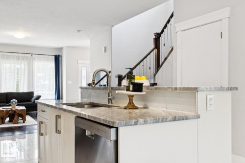 Kitchen island with integrated sink, stainless steel dishwasher, and stone countertops - 9919 79 Street Nw, Edmonton, AB 