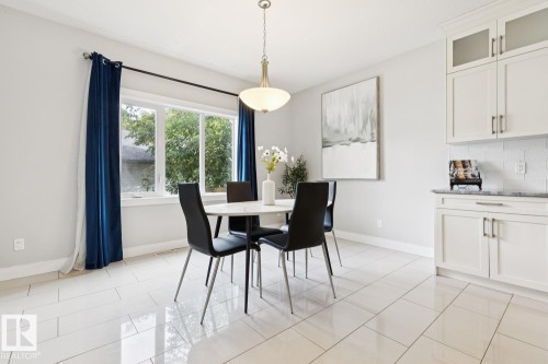 White tile flooring, white shaker-style cabinetry, dark countertop, subway tile backsplash, and a modern pendant light fixture - 9919 79 Street Nw, Edmonton, AB 
