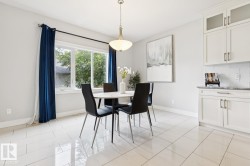White tile flooring, white shaker-style cabinetry, dark countertop, subway tile backsplash, and a modern pendant light fixture - 