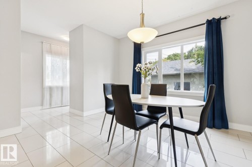 Polished white tile flooring, contemporary ceiling light fixture, and a large window providing ample natural light - 9919 79 Street Nw, Edmonton, AB 