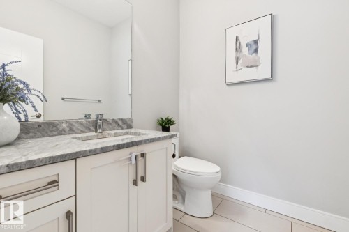 Vanity with integrated sink, polished chrome faucet, expansive wall mirror, and modern tile flooring - 9919 79 Street Nw, Edmonton, AB 