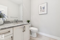 Vanity with integrated sink, polished chrome faucet, expansive wall mirror, and modern tile flooring - 