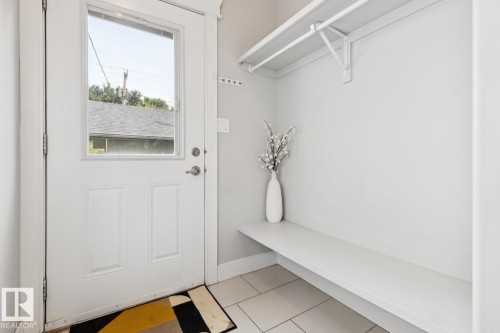 White paneled door with upper glass pane, tiled flooring, built-in shelving, and a hanging rod - 9919 79 Street Nw, Edmonton, AB 