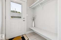 White paneled door with upper glass pane, tiled flooring, built-in shelving, and a hanging rod - 