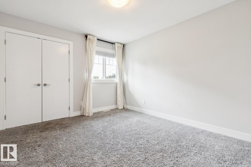 Neutral wall color, plush grey carpet, double closet doors, white trim, and a window with white blinds - 9919 79 Street Nw, Edmonton, AB 