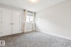 Neutral wall color, plush grey carpet, double closet doors, white trim, and a window with white blinds - 