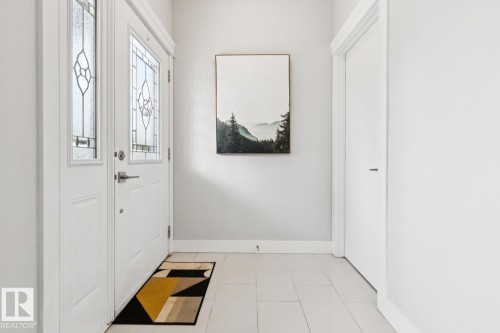 Entryway featuring a white door with leaded glass, white trim, and light-toned tile flooring - 9919 79 Street Nw, Edmonton, AB 