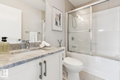 White vanity with rectangular undermount sink, stone countertop, chrome faucet, and coordinating hardware - 9919 79 Street Nw, Edmonton, AB 