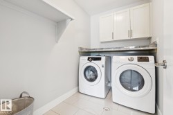 Laundry area with overhead white cabinetry, a single white wall shelf, and a countertop surface - 