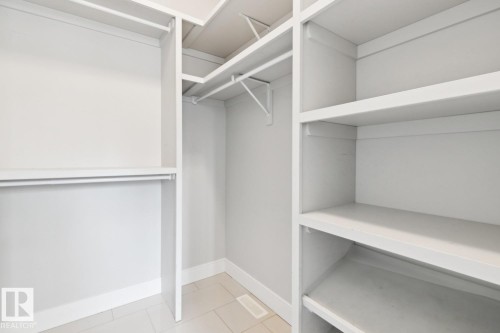 Walk-in closet with integrated shelving, multiple hanging rods, and tiled flooring - 9919 79 Street Nw, Edmonton, AB 