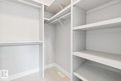 Walk-in closet with integrated shelving, multiple hanging rods, and tiled flooring - 