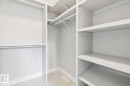 Walk-in closet with integrated shelving, multiple hanging rods, and tiled flooring - 9919 79 Street Nw, Edmonton, AB 