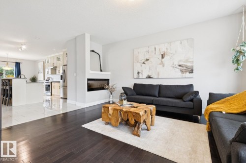 Wood-finish flooring, built-in fireplace, recessed lighting, white wall finishes, and a kitchen island with seating - 9919 79 Street Nw, Edmonton, AB 