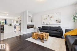 Wood-finish flooring, built-in fireplace, recessed lighting, white wall finishes, and a kitchen island with seating - 