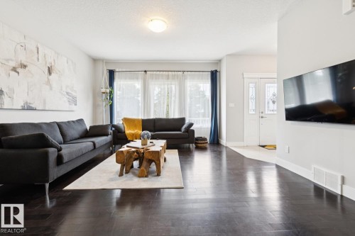 Dark wood-finish flooring throughout, bright white walls, and a multi-panel front door with decorative glass inserts - 9919 79 Street Nw, Edmonton, AB 
