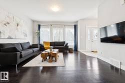 Dark wood-finish flooring throughout, bright white walls, and a multi-panel front door with decorative glass inserts - 