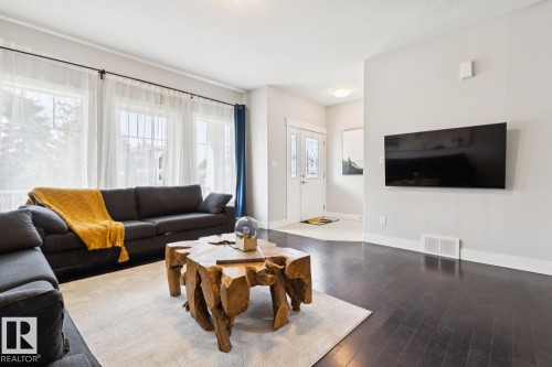 Dark wood-finish flooring, white baseboards, multiple large windows, and a white entry door with decorative glass inserts - 9919 79 Street Nw, Edmonton, AB 