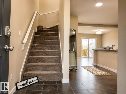 Tiled entryway with carpeted stairs and white handrail - 5407 14 Avenue Sw, Edmonton, AB 