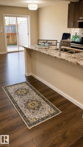Kitchen featuring wood-finish flooring, granite-style countertops, dual basin sink, and wood cabinetry - 5407 14 Avenue Sw, Edmonton, AB 