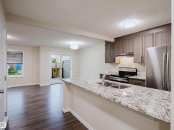 Open-concept kitchen with granite countertops, stainless steel appliances, and wood-finish flooring - 