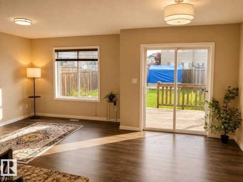 Wood-finish flooring, neutral wall tones, recessed lighting, white trim window with blinds, and white trim sliding glass door to exterior deck - 5407 14 Avenue Sw, Edmonton, AB 