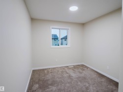 Neutral-toned walls, recessed ceiling lighting, light-colored carpeting, a window with white trim, and white baseboards - 